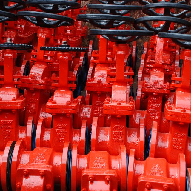 Close rows of red gate valves with black handwheels